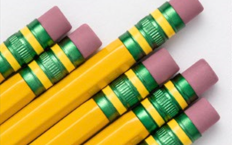 Group of yellow pencils with green and purple erasers arranged neatly.