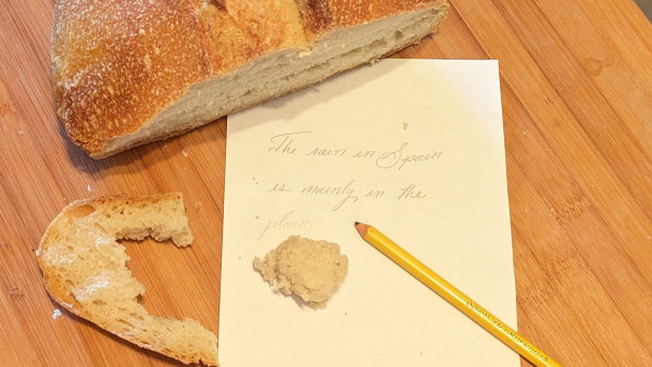 Artisan bread with handwritten note and pencil on wooden surface.